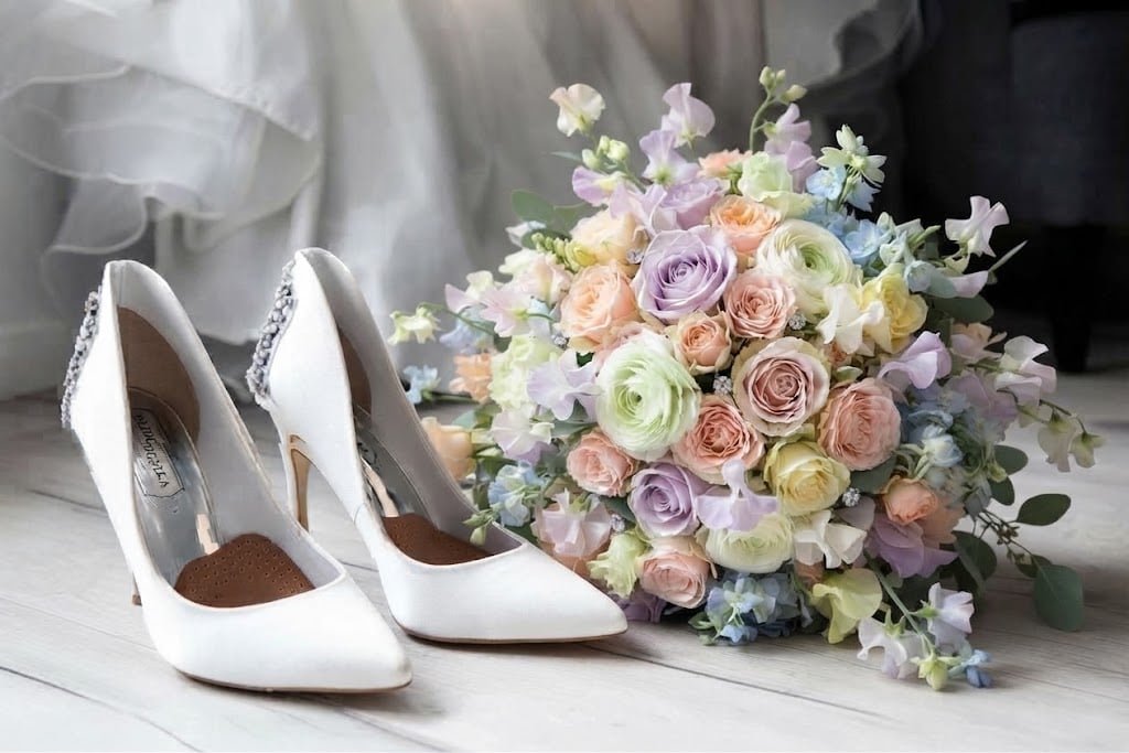Brautschuhe neben einem Strauß rosa Rosen